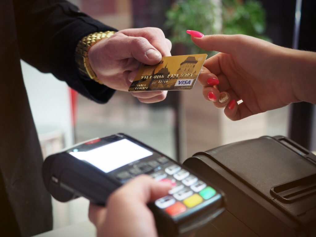 man handing is visa card over to a sales assistant holding a credit card machine